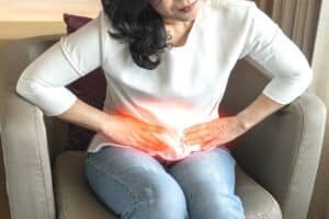 A woman sitting in a chair, bent over because of pelvic pain